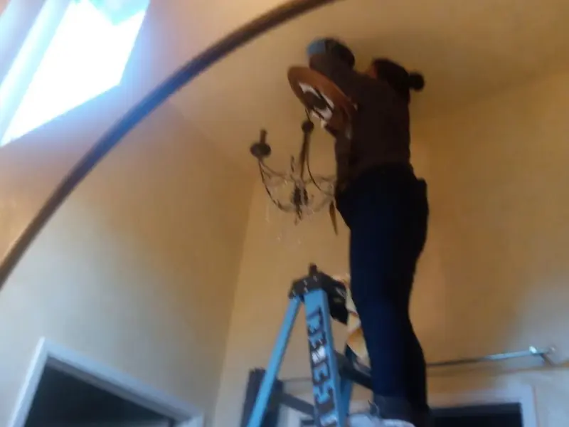 Electrician installing a chandelier in a Waco residence